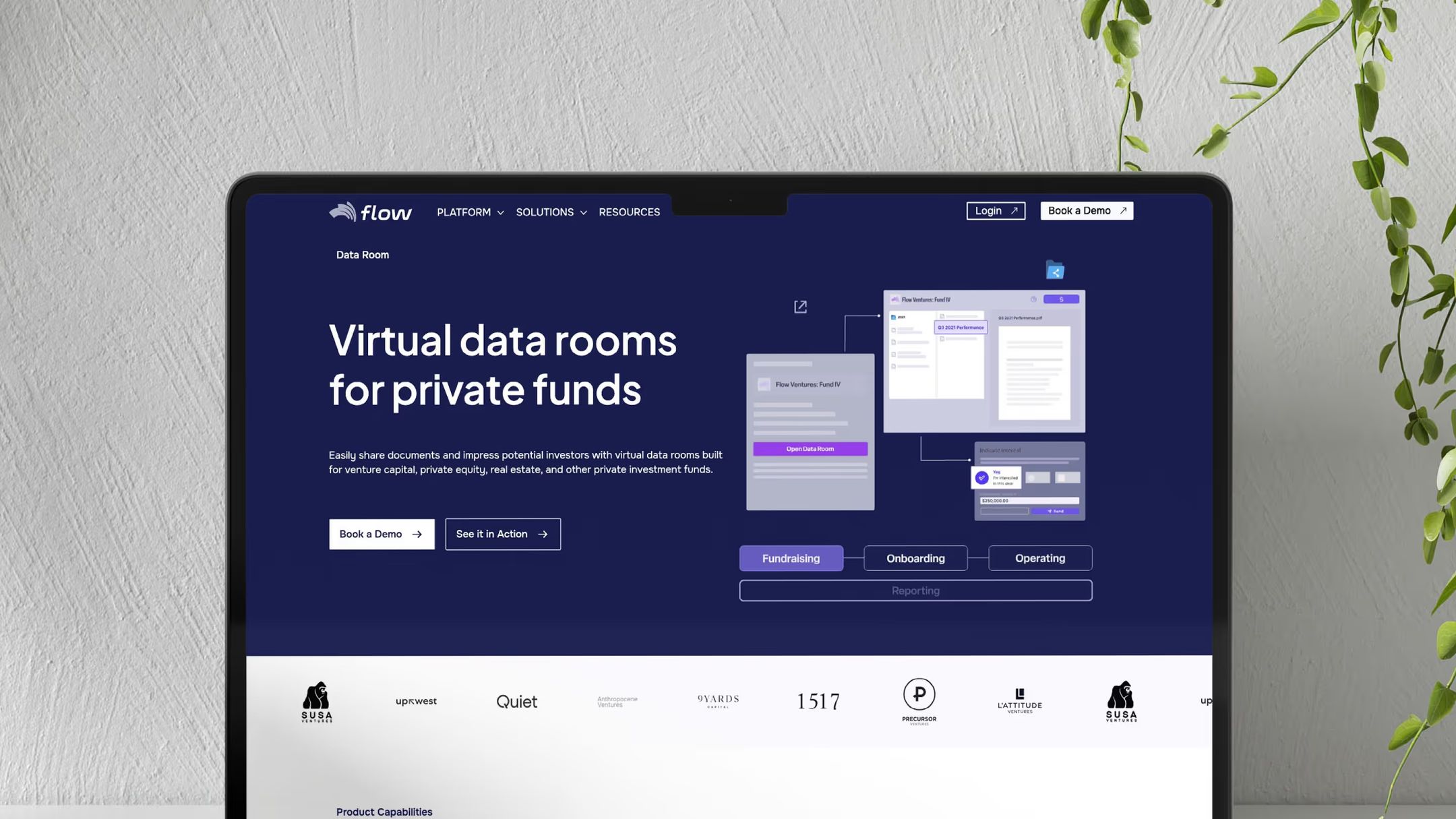 Flow virtual data rooms website on a desktop monitor beside a plant